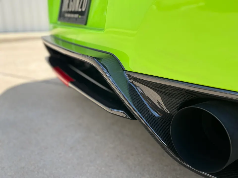 Close-up of a bright green car's rear, showcasing a carbon fiber diffuser and a large black exhaust tip.