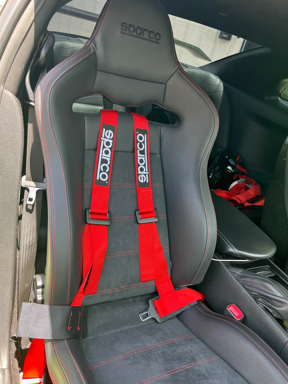 Sparco racing seat with red harnesses and red stitching in a performance car interior