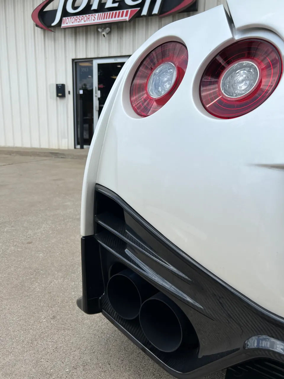Rear view of a white Nissan GT-R R35 showcasing aftermarket exhaust tips and carbon fiber diffuser at Jotech Motorsports.