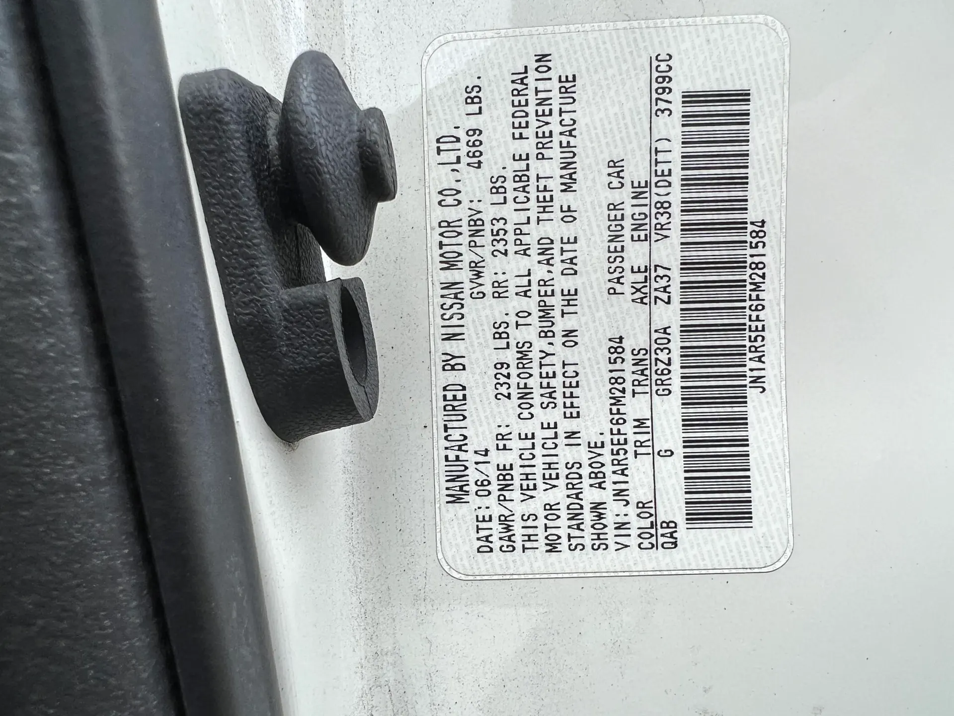 Close-up of a Nissan GT-R door jamb sticker showing VIN, engine code VR38(DETT), and manufacturing details.