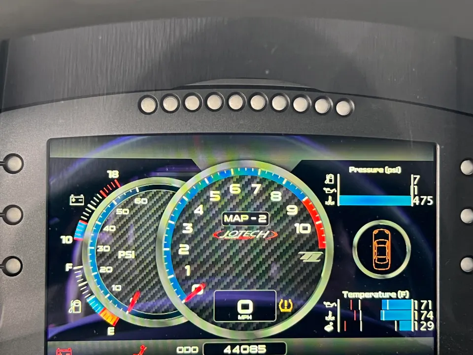 A close-up of a Jotech digital dashboard displaying various vehicle metrics like pressure, temperature, and speed.