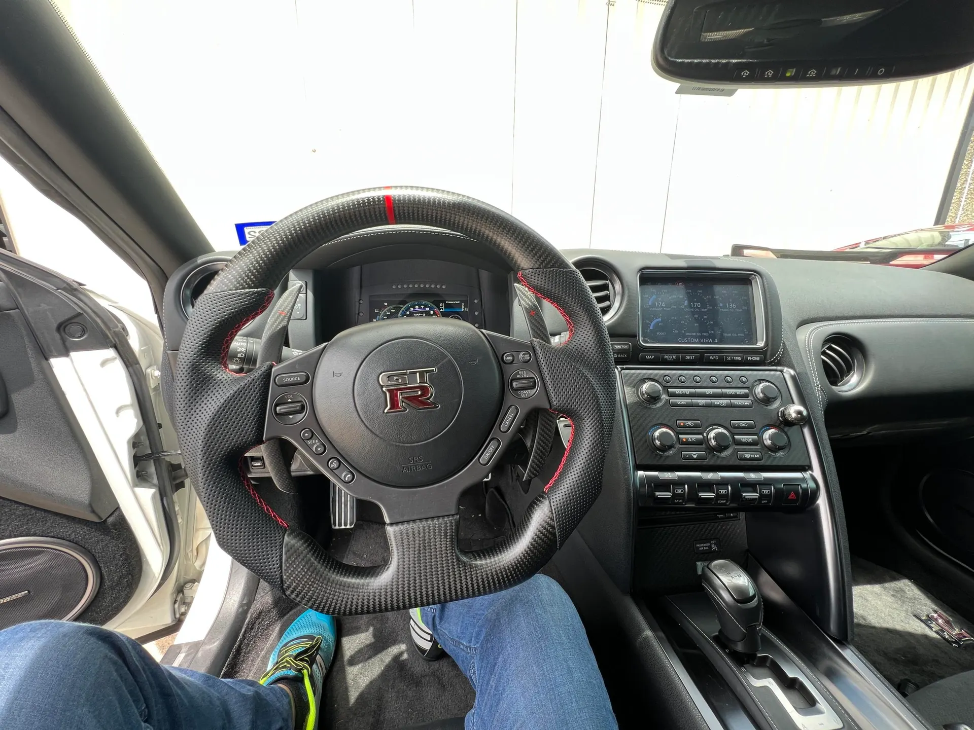 Interior view of a Nissan GT-R featuring a carbon fiber steering wheel, dashboard, and center console.
