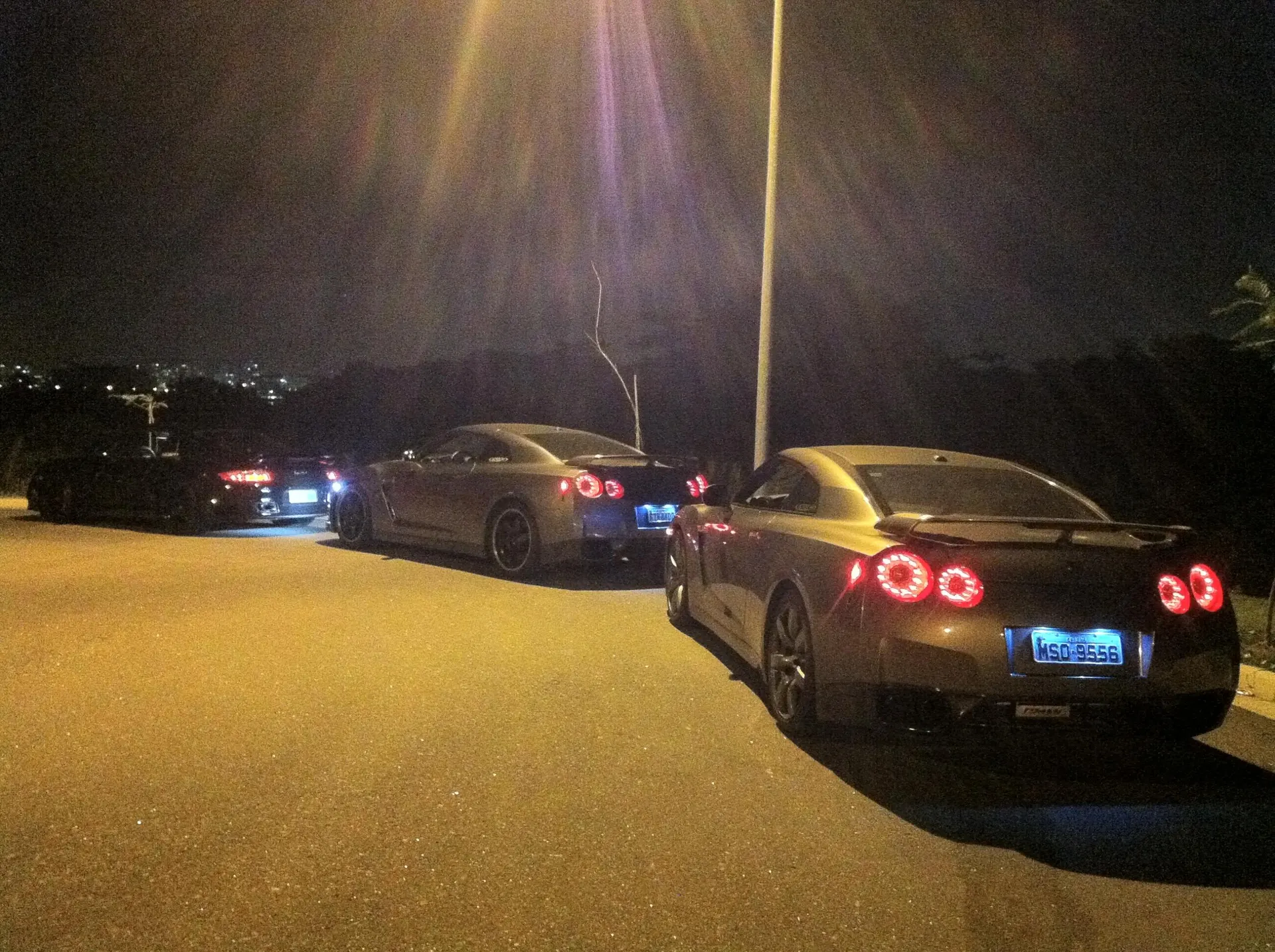 Multiple Nissan GT-R R35 performance cars parked at a night car meet, showcasing their distinctive taillights.