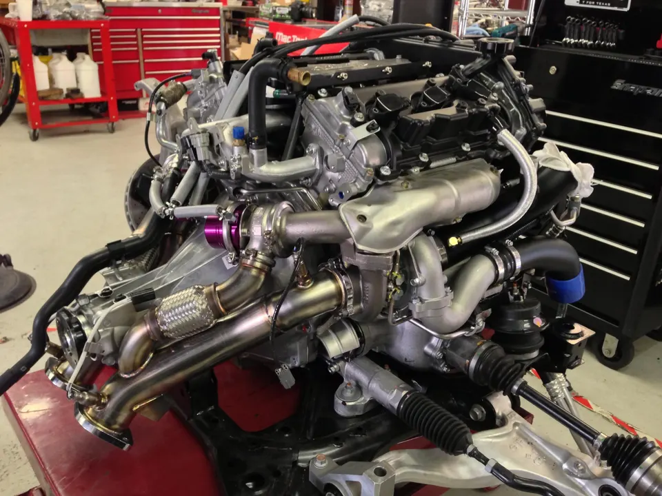 High-performance engine assembly with twin turbochargers, wastegates, and custom exhaust manifolds in a workshop.