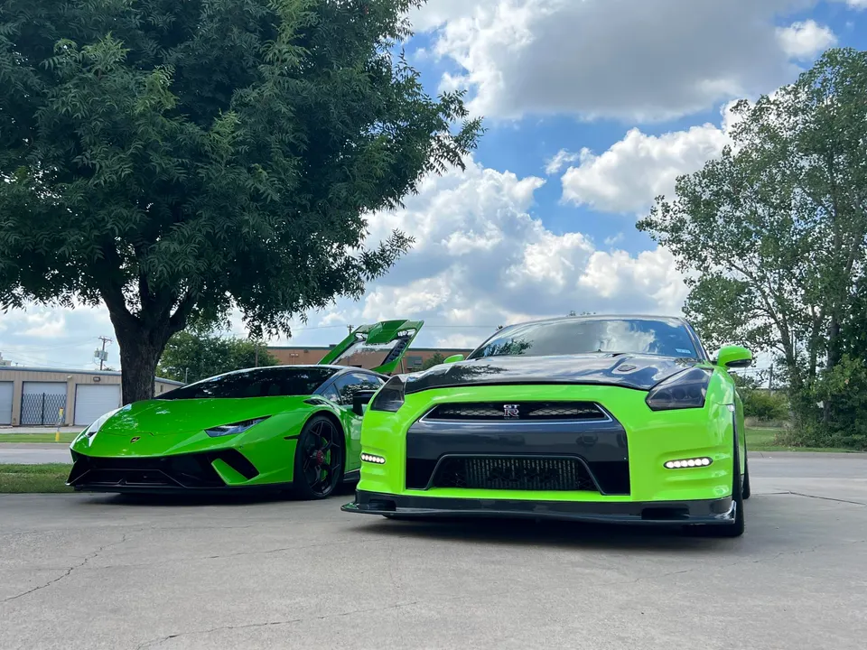 Two bright green supercars, a Lamborghini Huracan and a Nissan GT-R, parked outdoors under a cloudy sky.