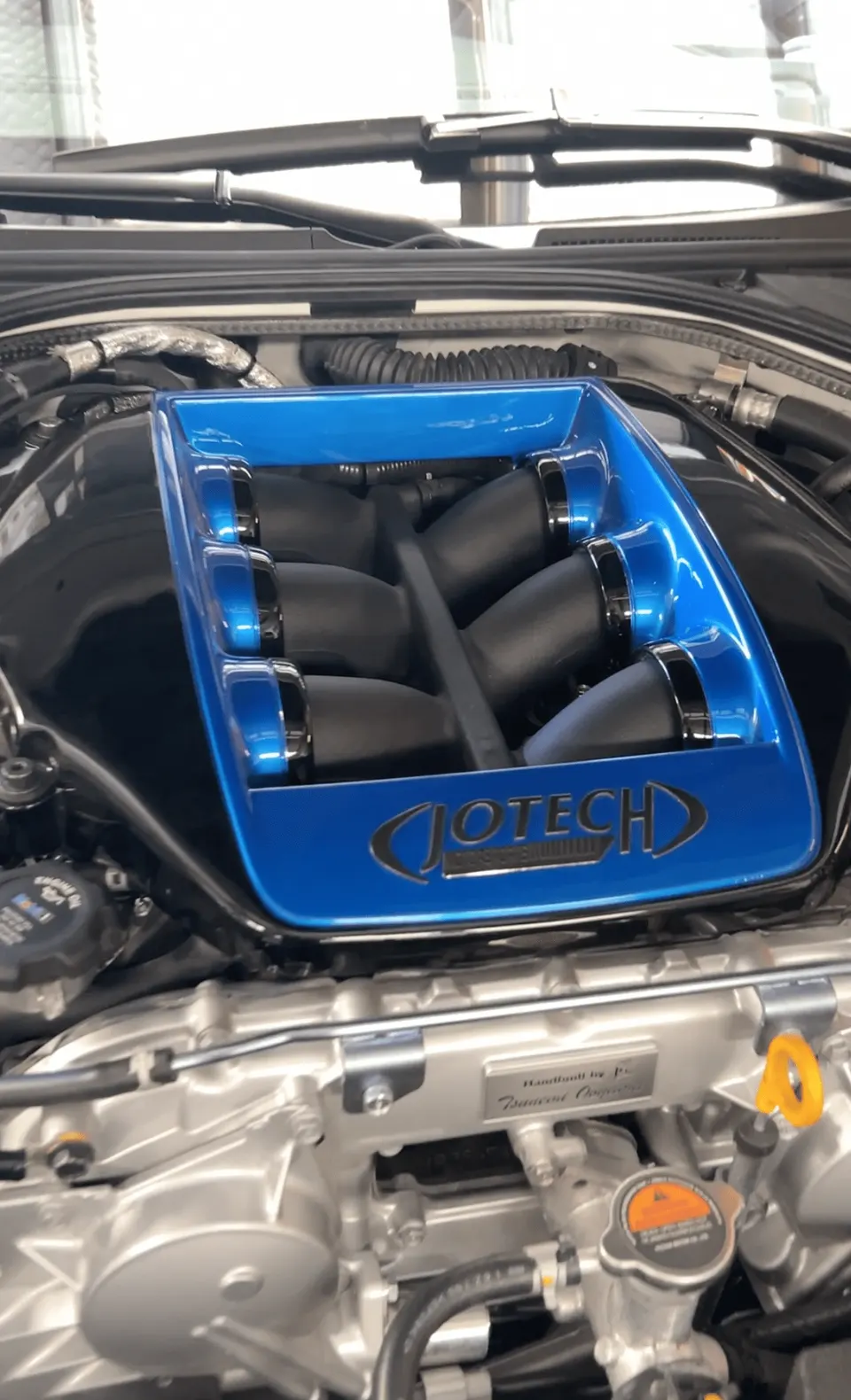 Close-up of a blue Jotech intake manifold in a Nissan GT-R engine bay, showcasing the custom performance part.