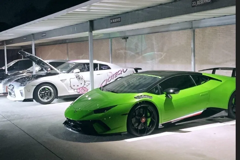 A green Lamborghini Huracan and a white Nissan GT-R with Hello Kitty livery parked in a garage.
