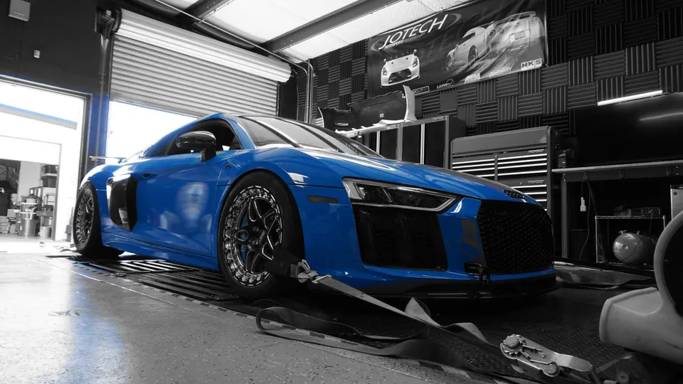 Blue Audi R8 strapped down on a dynamometer at a performance tuning shop.