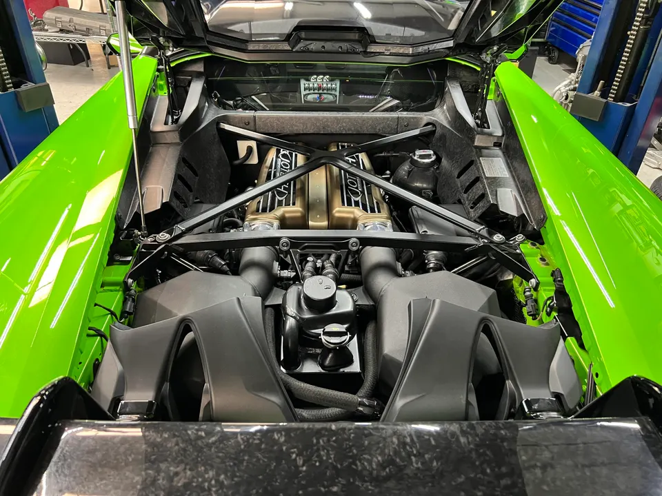 Bright green Lamborghini Huracan engine bay with V10 engine visible in a performance tuning shop.