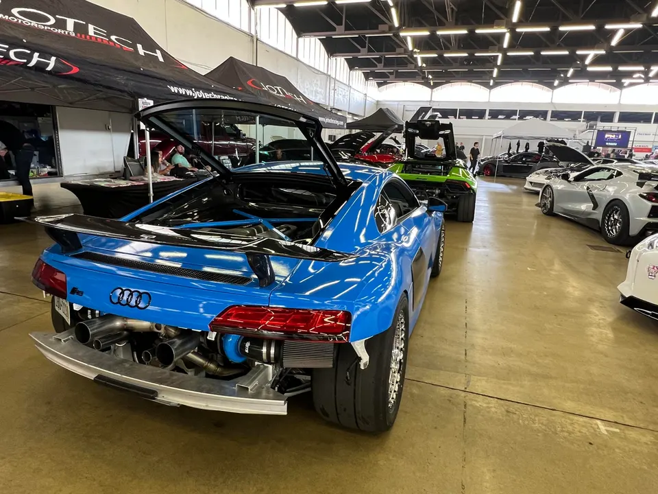 Highly modified blue Audi R8 with exposed turbocharger, intercooler, and custom exhaust system at a car show.