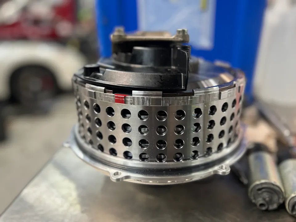Close-up of a high-performance fuel pump assembly on a workbench in a tuning shop.