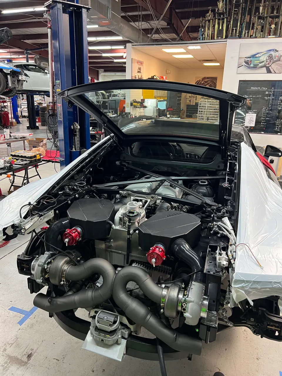 A Lamborghini Huracan undergoing a twin-turbo installation in a performance tuning shop, showcasing the custom engine setup.