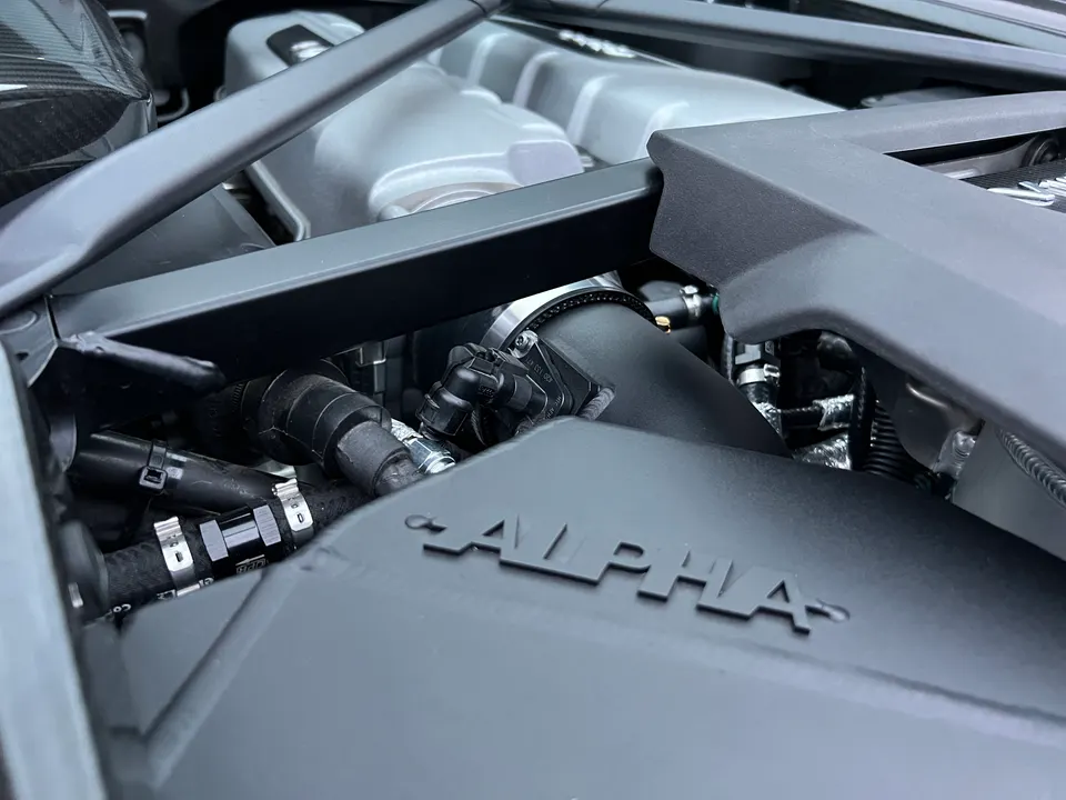 Close-up of an Alpha Performance intake system in a supercar engine bay, showcasing performance upgrades.