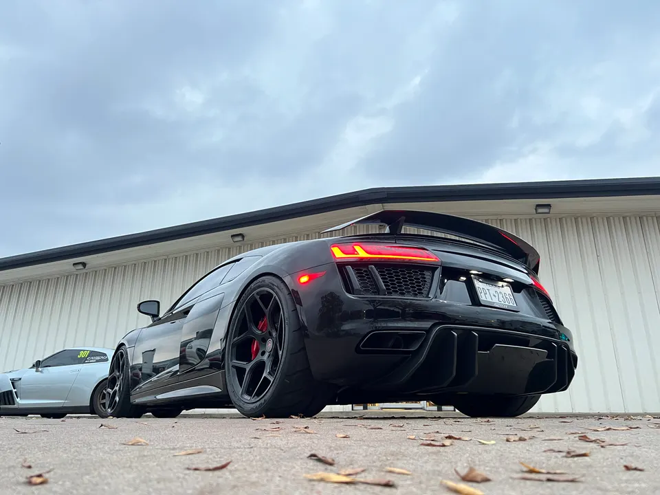 Low angle rear view of a black Audi R8 with a large rear wing, custom wheels, and an aggressive diffuser.