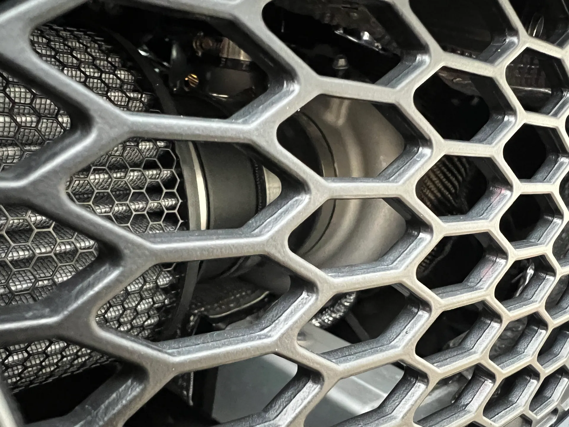 Close-up view of a performance air filter and intake system behind a honeycomb grille.