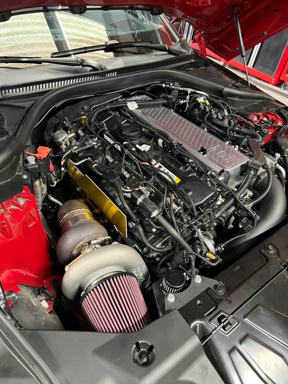 Close-up of a modified Toyota Supra A90 engine bay featuring a large aftermarket turbocharger and intake manifold.