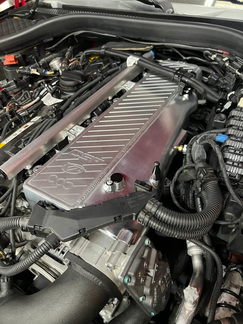 Close-up of a modified B58 engine bay in a Toyota Supra, featuring an aftermarket intake manifold.