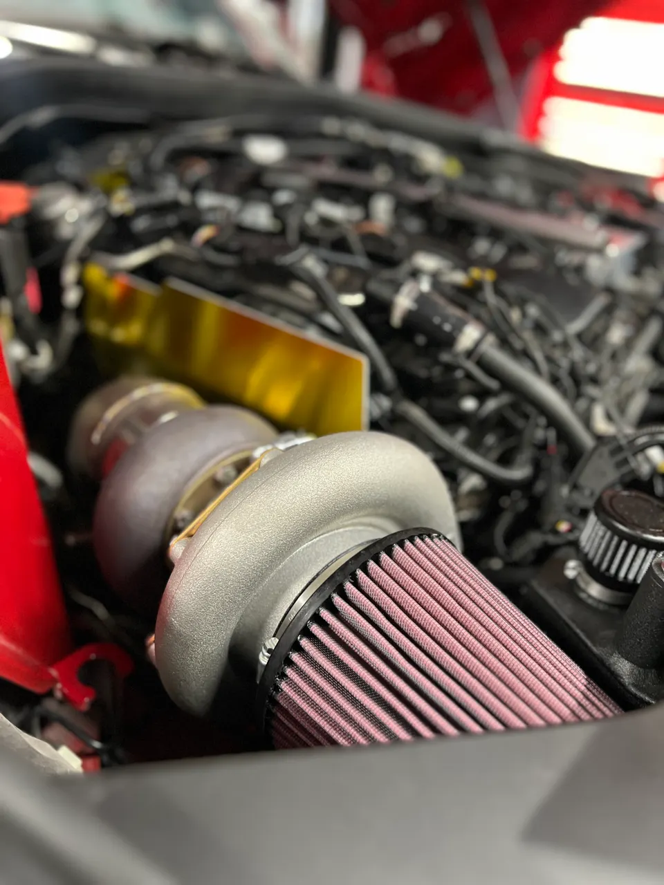 A close-up of a high-performance turbocharger and air filter in a custom-built engine bay.