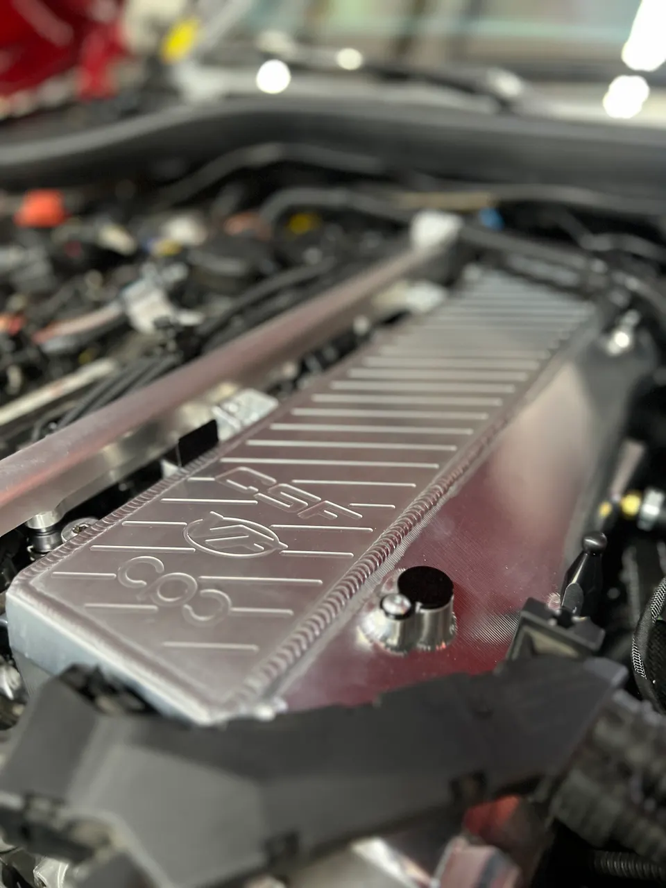 Close-up of a CSF intercooler in a performance car's engine bay, showcasing the engraved logo and finned design.