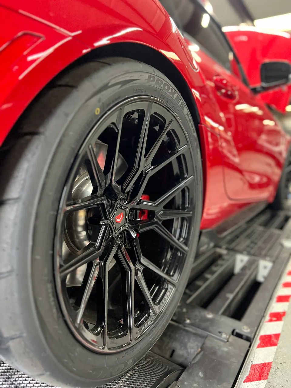 Red performance car on a dyno, showcasing black Vossen wheels and Toyo Proxes tires.