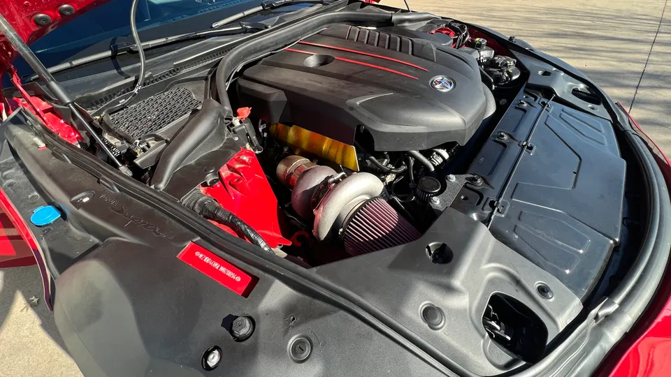 A red Toyota Supra's engine bay showcasing a large aftermarket turbocharger and performance air intake system.