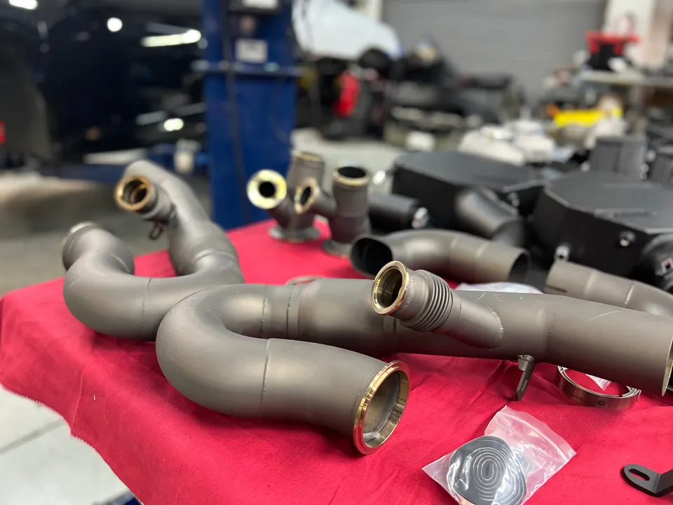 Aftermarket exhaust pipes and performance parts laid out on a red table in a tuning shop.