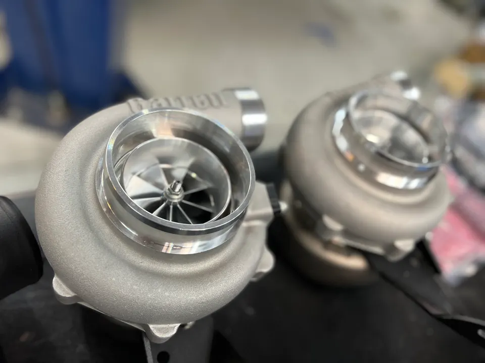 Two new Garrett turbochargers on a workbench in a performance tuning shop, ready for installation.