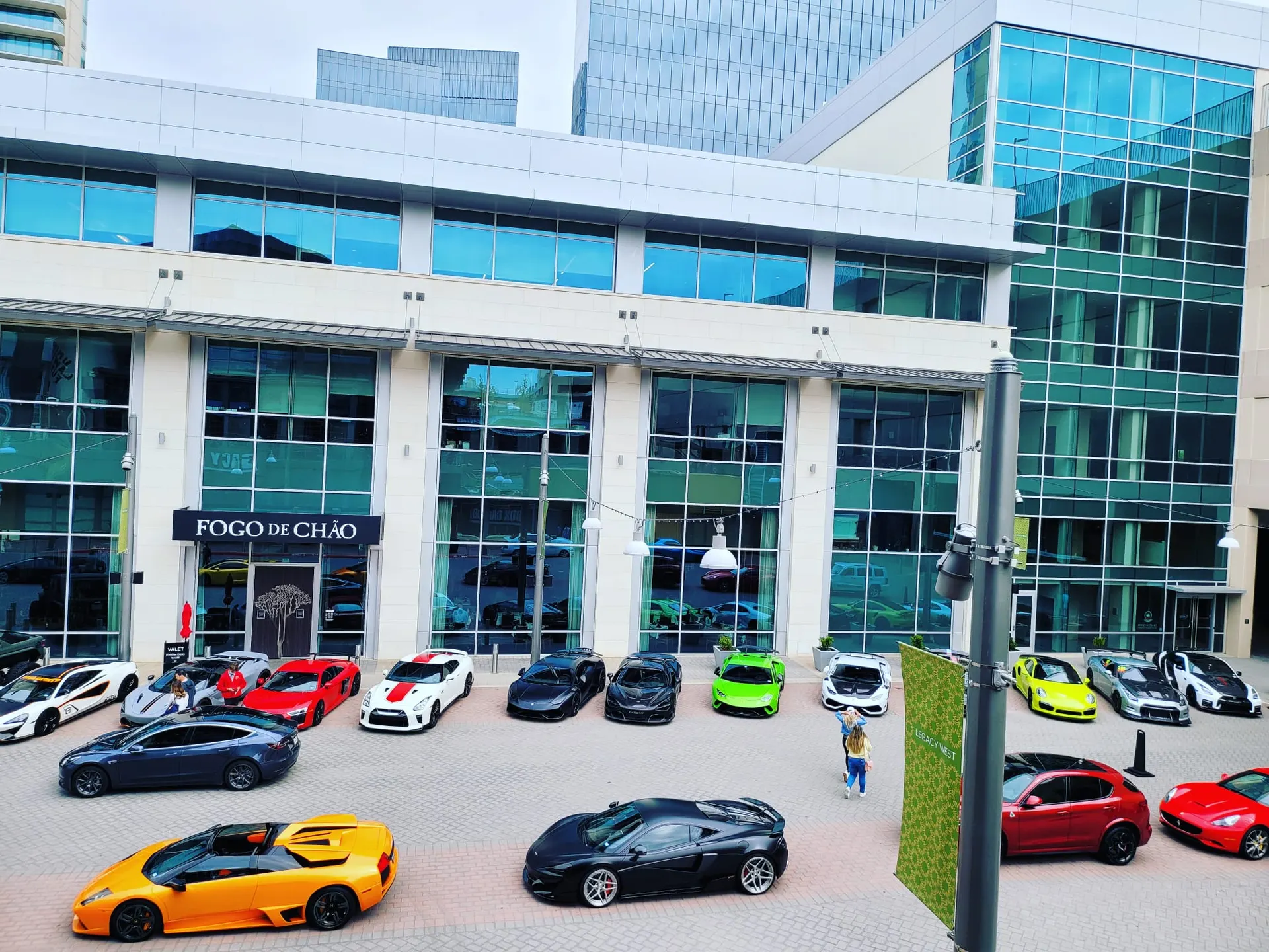 A gathering of various supercars including Lamborghinis, McLarens, and Nissan GT-Rs parked outside Fogo de Ch
ao.