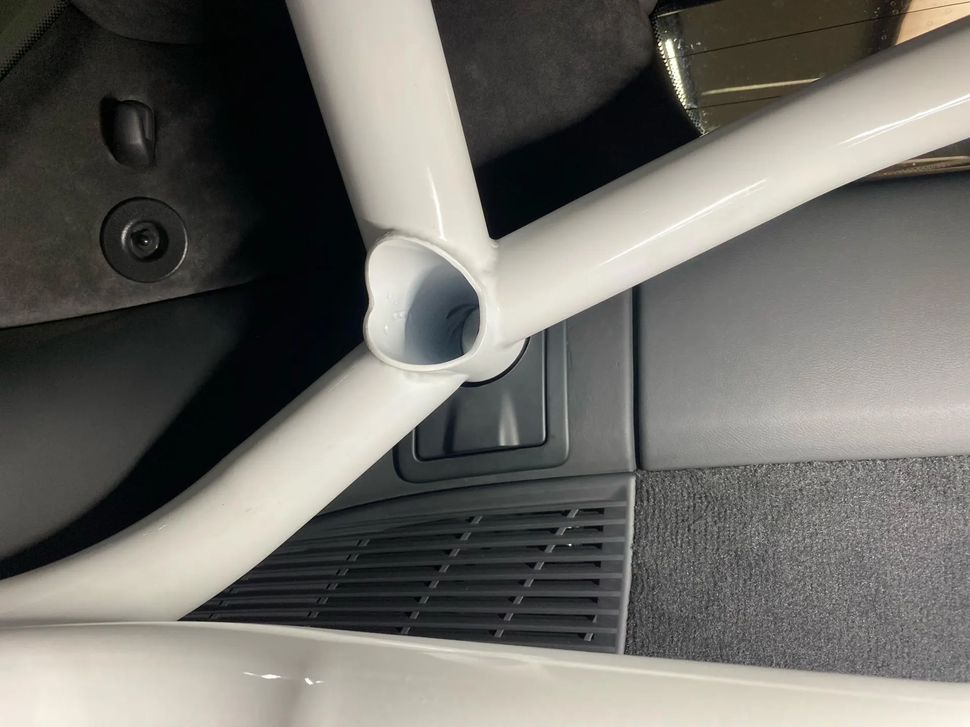 Close-up view of a white roll cage installed in a car's interior, highlighting the safety structure.