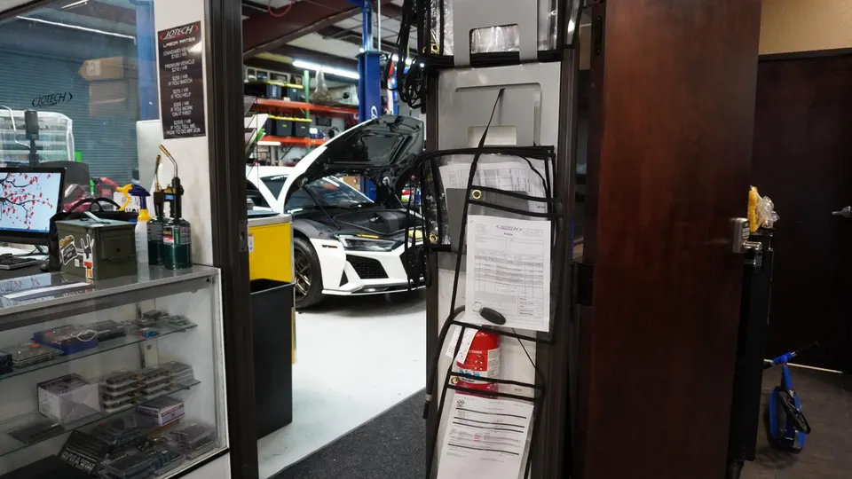 Interior view of Jotech Motorsports shop facility with an Audi R8 on a lift and a reception desk.
