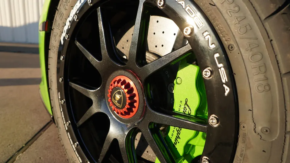 Close-up of a Lamborghini's black forged wheel with a red center cap, vibrant green brake caliper, and Pirelli tire.