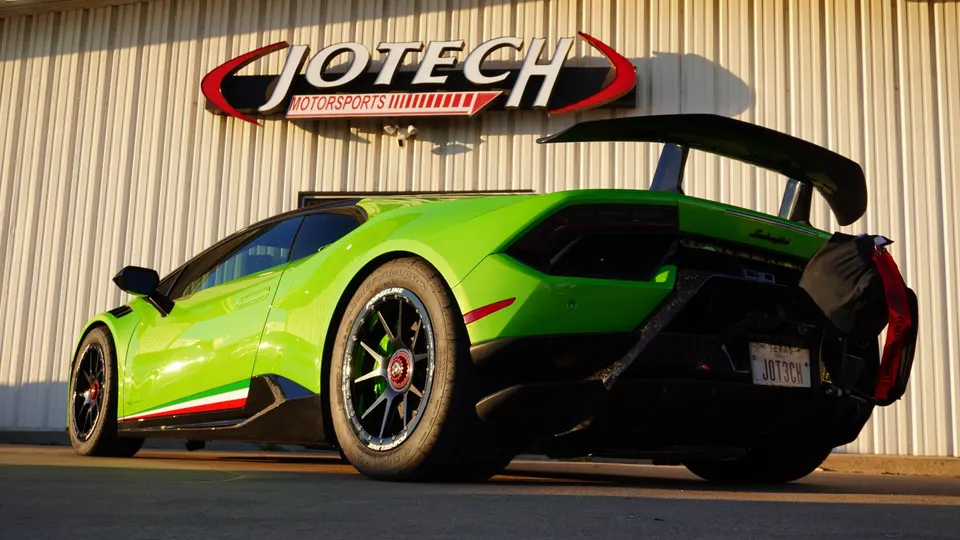 Green Lamborghini Huracan with a large rear wing and custom wheels parked outside Jotech Motorsports.