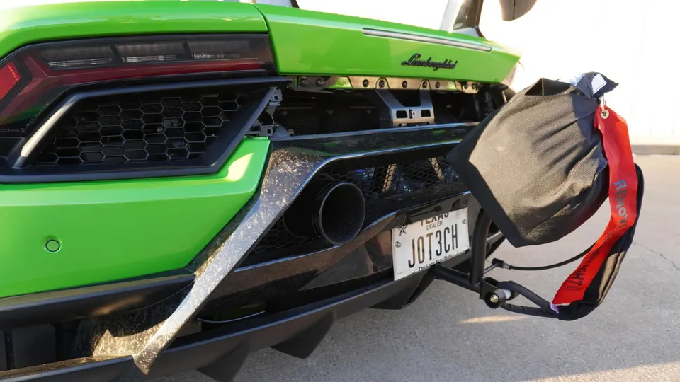 Rear of a green Lamborghini with a drag parachute and performance exhaust, ready for a track run.