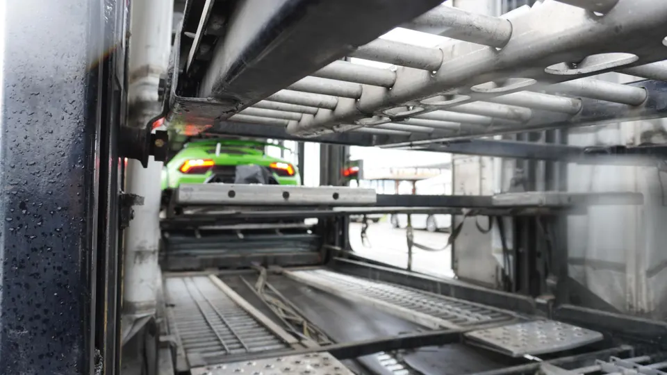 Green Lamborghini Huracan supercar being transported in a car carrier, part of Jotech Motorsports' shop logistics.