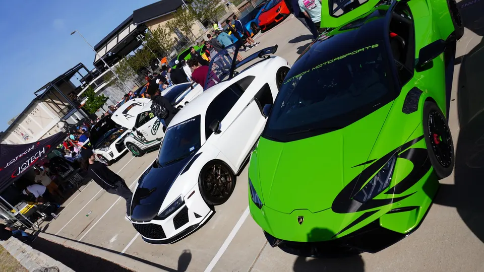 Jotech Motorsports car meet featuring a green Lamborghini Huracan, white Audi R8, and other modified performance cars at an outdoor event.