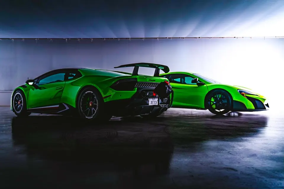 Two vibrant green supercars, a Lamborghini Huracan and a McLaren, parked side-by-side in a professional studio setting.