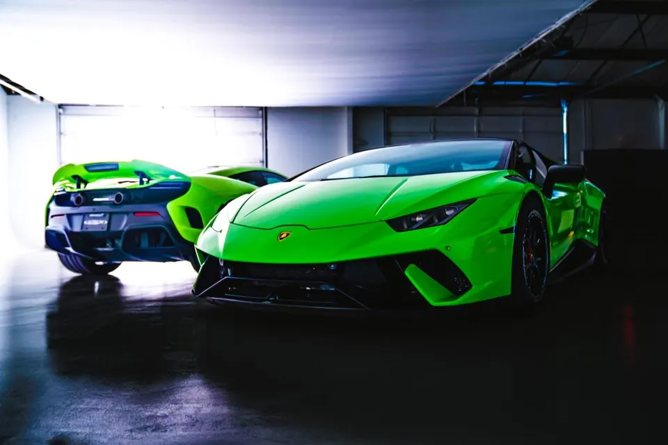 Two vibrant green supercars, a Lamborghini Huracan and a McLaren, parked side-by-side in a professional studio setting.