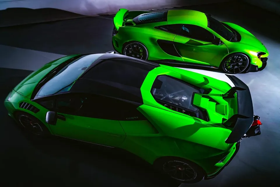 Two custom green supercars, a Lamborghini and a McLaren, parked in a studio setting with dramatic lighting.
