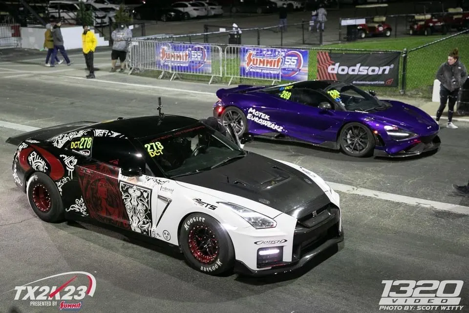 A white and black Nissan GT-R with custom livery and a purple McLaren 720S in the staging lanes at a drag strip during TX2K23.