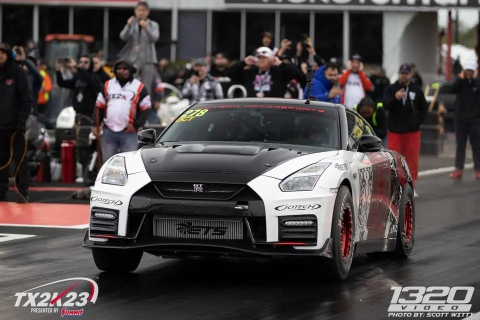 A white and black Jotech Motorsports Nissan GT-R on a drag strip, showcasing its front-mounted intercooler.