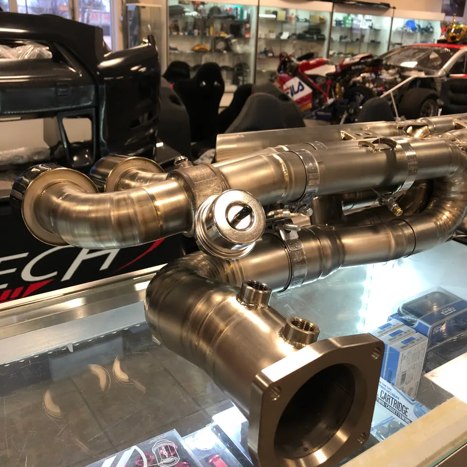 Titanium turbo manifold with wastegates on display at Jotech Motorsports performance tuning shop.