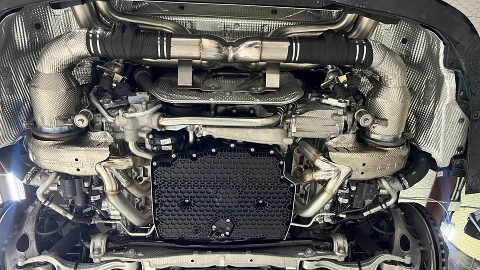 Underside view of a Porsche with Fabspeed exhaust headers and turbochargers installed in a shop.