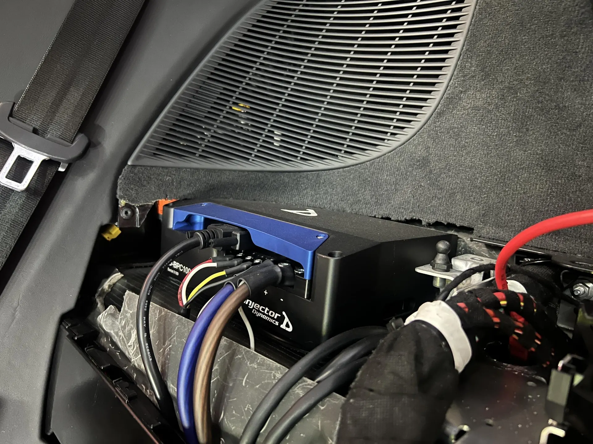Close-up of an Injector Dynamics electronic control unit installed in a car's rear interior with wiring.