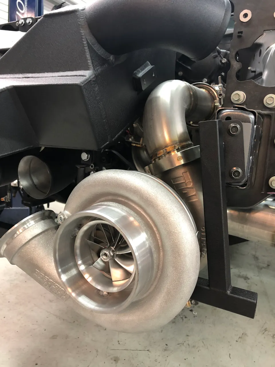A close-up view of a large Precision turbocharger installed in a high-performance engine bay with custom boost piping.
