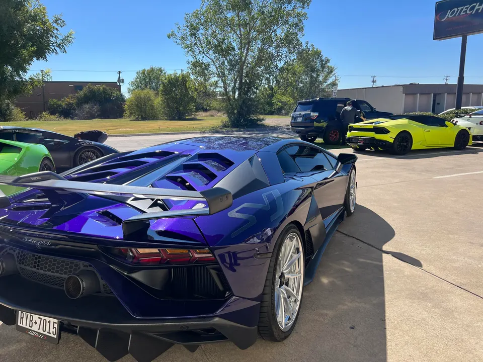 Purple Lamborghini supercar with custom wheels and a rear wing parked outside Jotech Motorsports with other exotic cars.