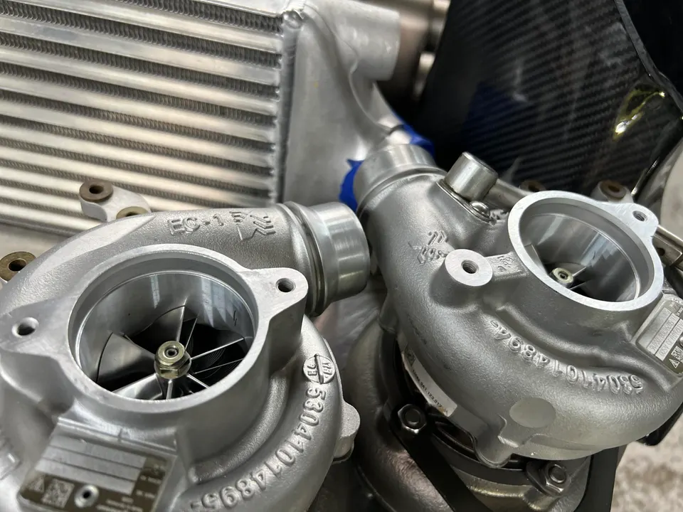 Close-up of two new turbochargers and an intercooler, ready for installation in a high-performance vehicle.