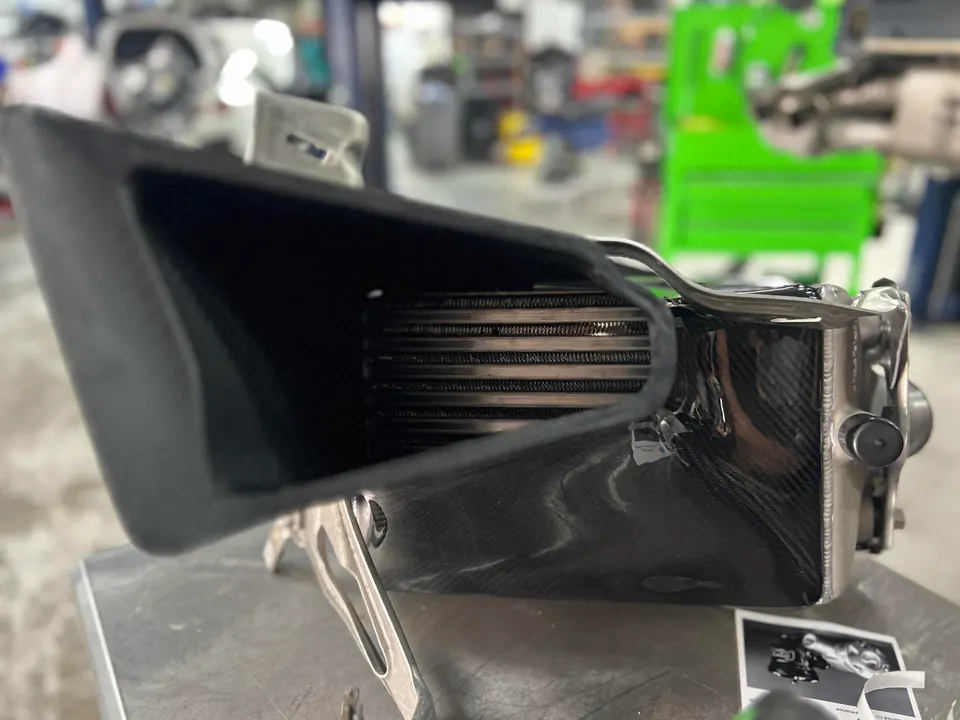 A carbon fiber intercooler on a workbench in a performance tuning shop.
