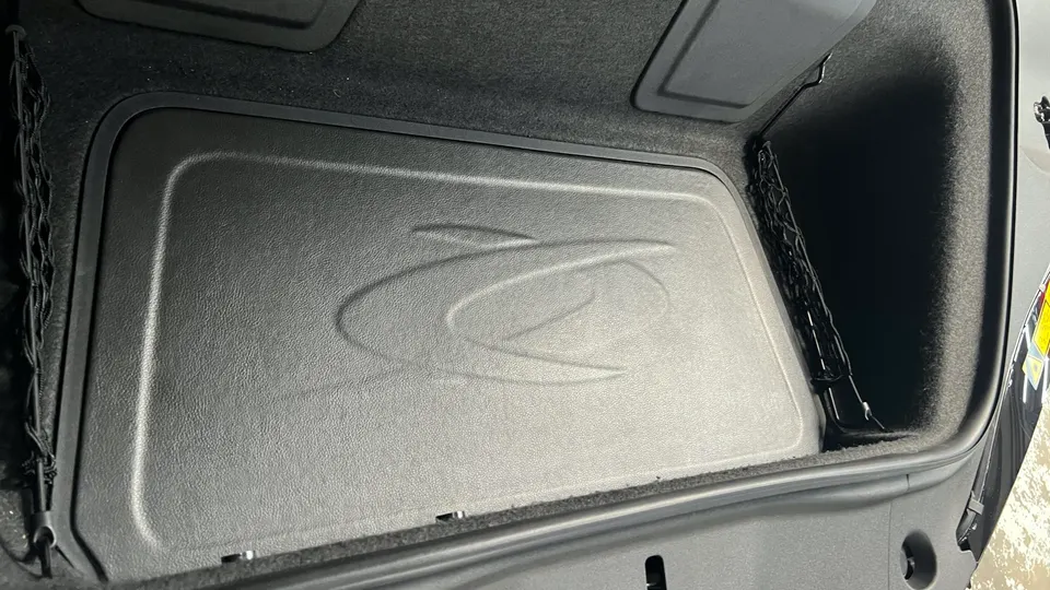 Custom subwoofer enclosure with an embossed logo in the trunk of a performance car, showcasing aftermarket audio.