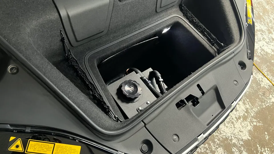 Peterson Systems fluid tank with AN fittings installed in a car's trunk compartment.