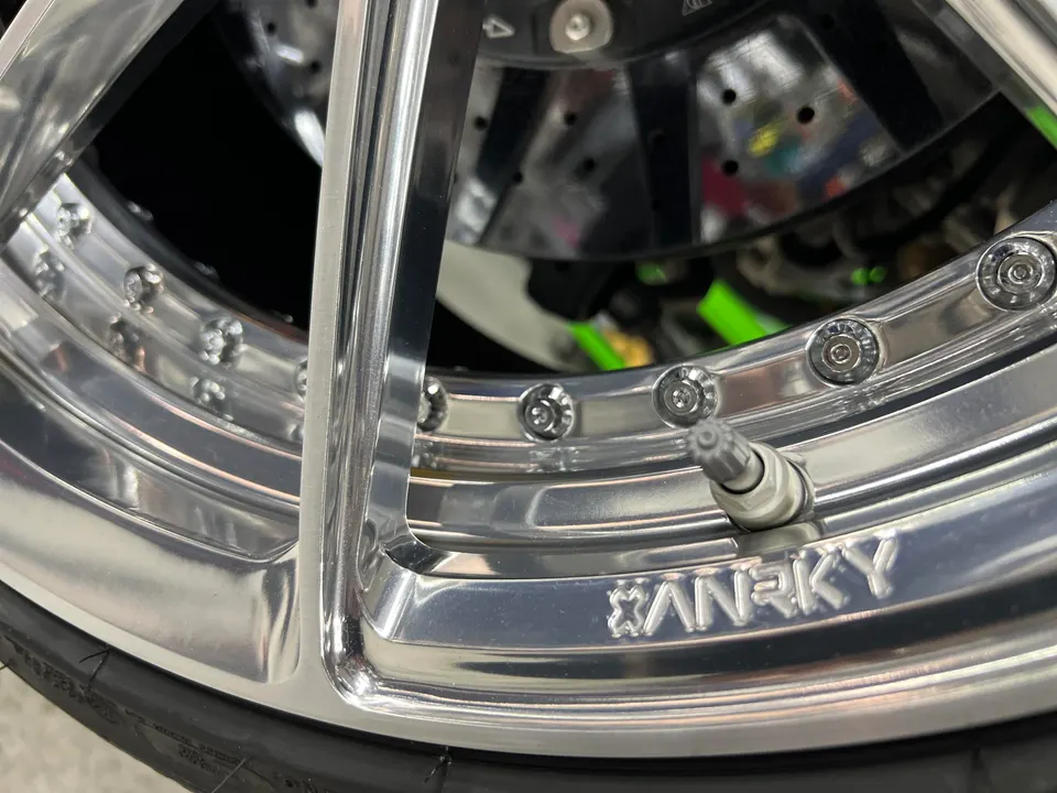 Close-up of a polished ANRKY wheel with a tire and brake rotor visible, highlighting the valve stem.